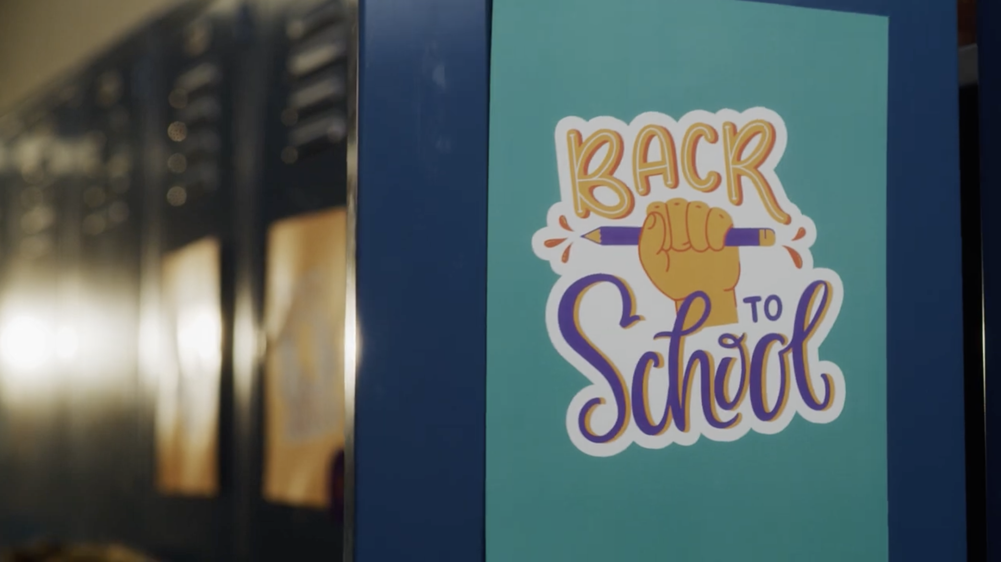 Several school lockers are visible with one in focus, a sign on it reads, "Back to School"