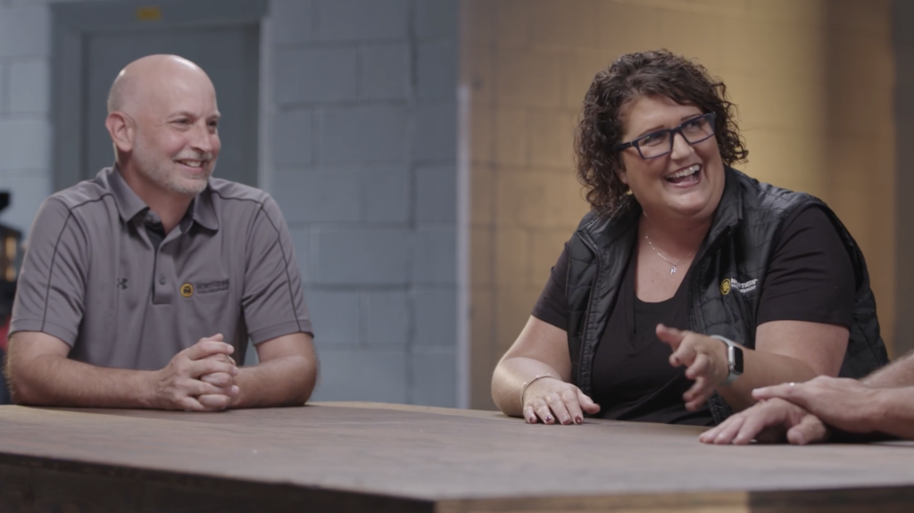 A man and woman laugh as they speak together at a table